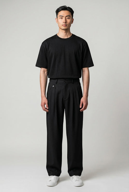 Tuck It black pleated trousers with a relaxed fit and button closure, paired with a black t-shirt.