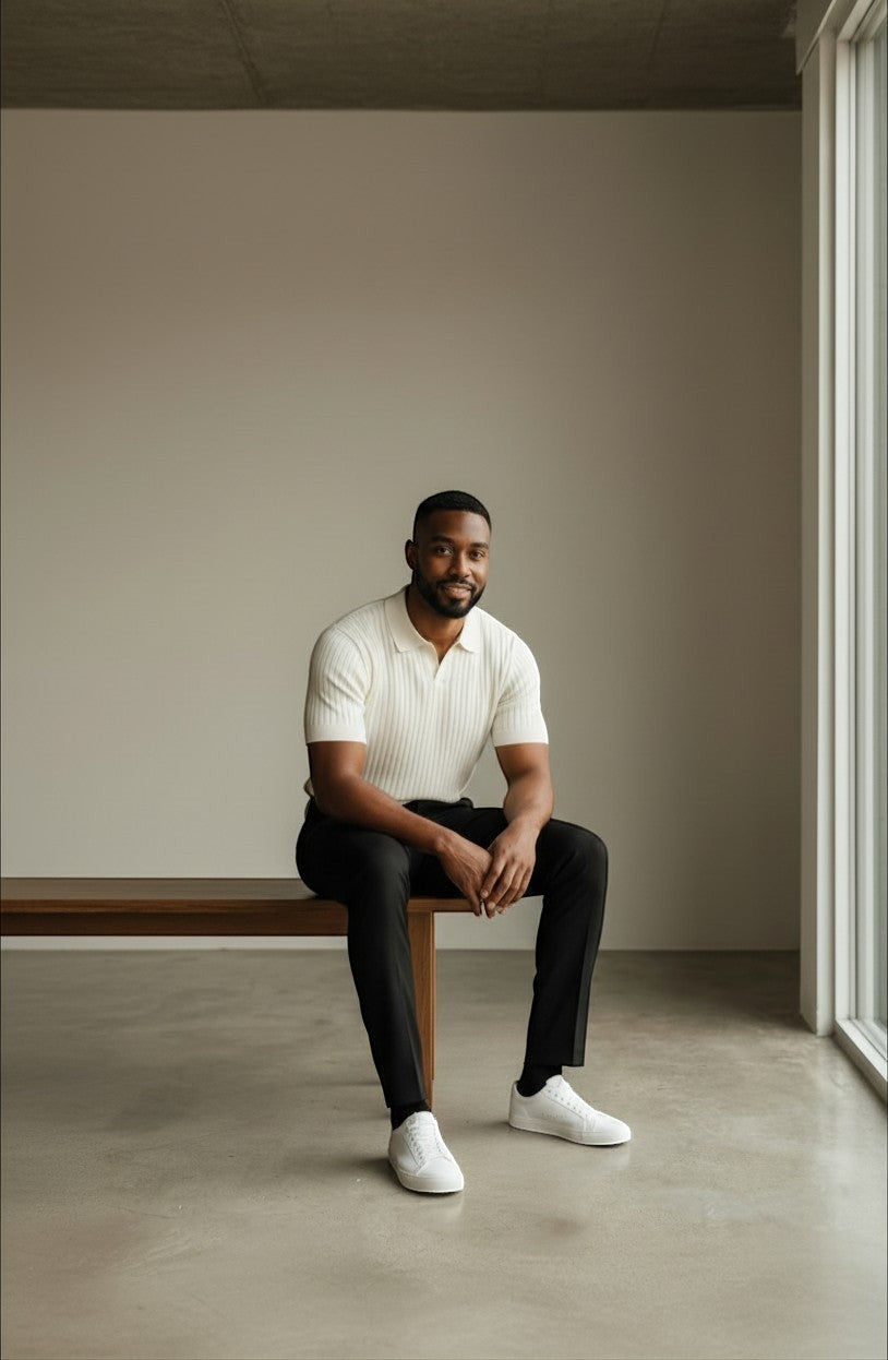 Tuck It cream ribbed knit short sleeve polo shirt with a spread collar and black trousers.