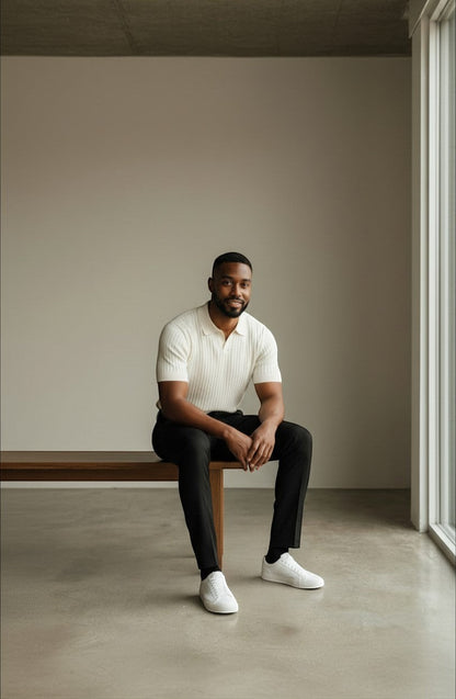 Tuck It cream ribbed knit short sleeve polo shirt with a spread collar and black trousers.